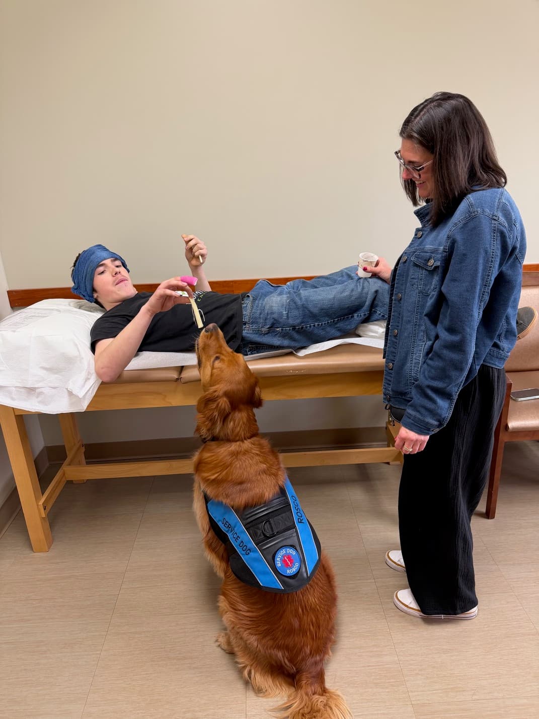 Rosco wearing his service dog vest during a visit with a patient on an exam table